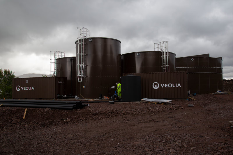 Brown water storage tanks with grey skies in the background