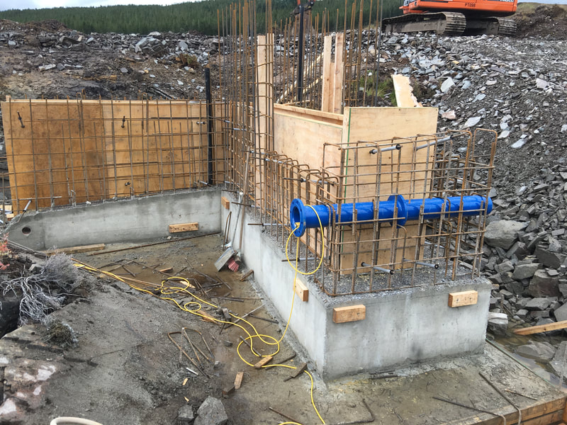 A small intake chamber during the early stages of construction, showing a poured concrete base with reinforcing showing and some of the shuttering erected - also in place is the blue compensation flow pipe