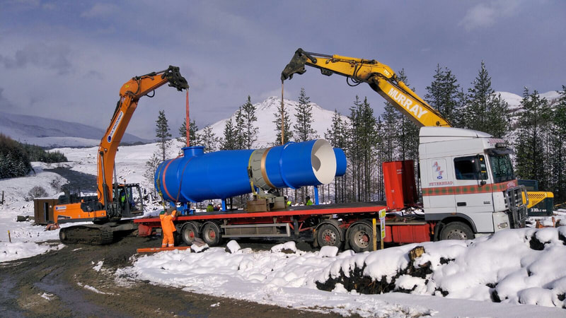 large section of pipe being offloaded from a lorry with 2 excavators