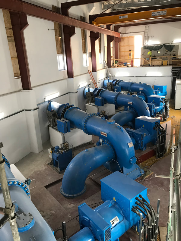 blue Turbines in the lower level inside a large powerhouse