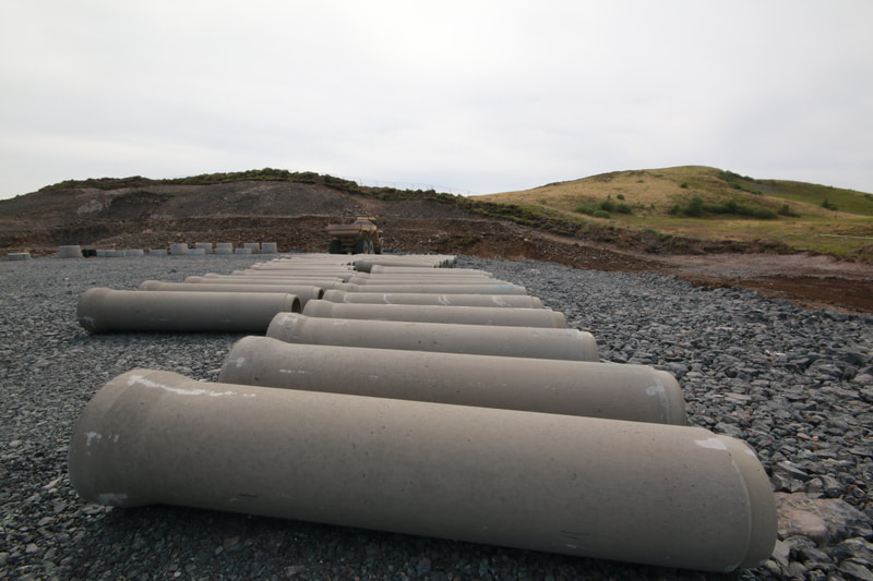 2 rows of concrete pipes lying on crushed rock